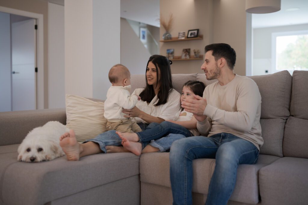 7 Urgent Signs Your Heater Needs Service 1 Happy family is spending time together at home, sitting on a comfortable sofa in their living room, talking, playing and bonding with their baby, daughter and dog